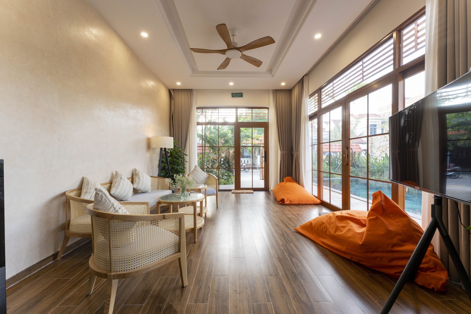Living room with rattan sofa, bean bags and glass doors to the pool