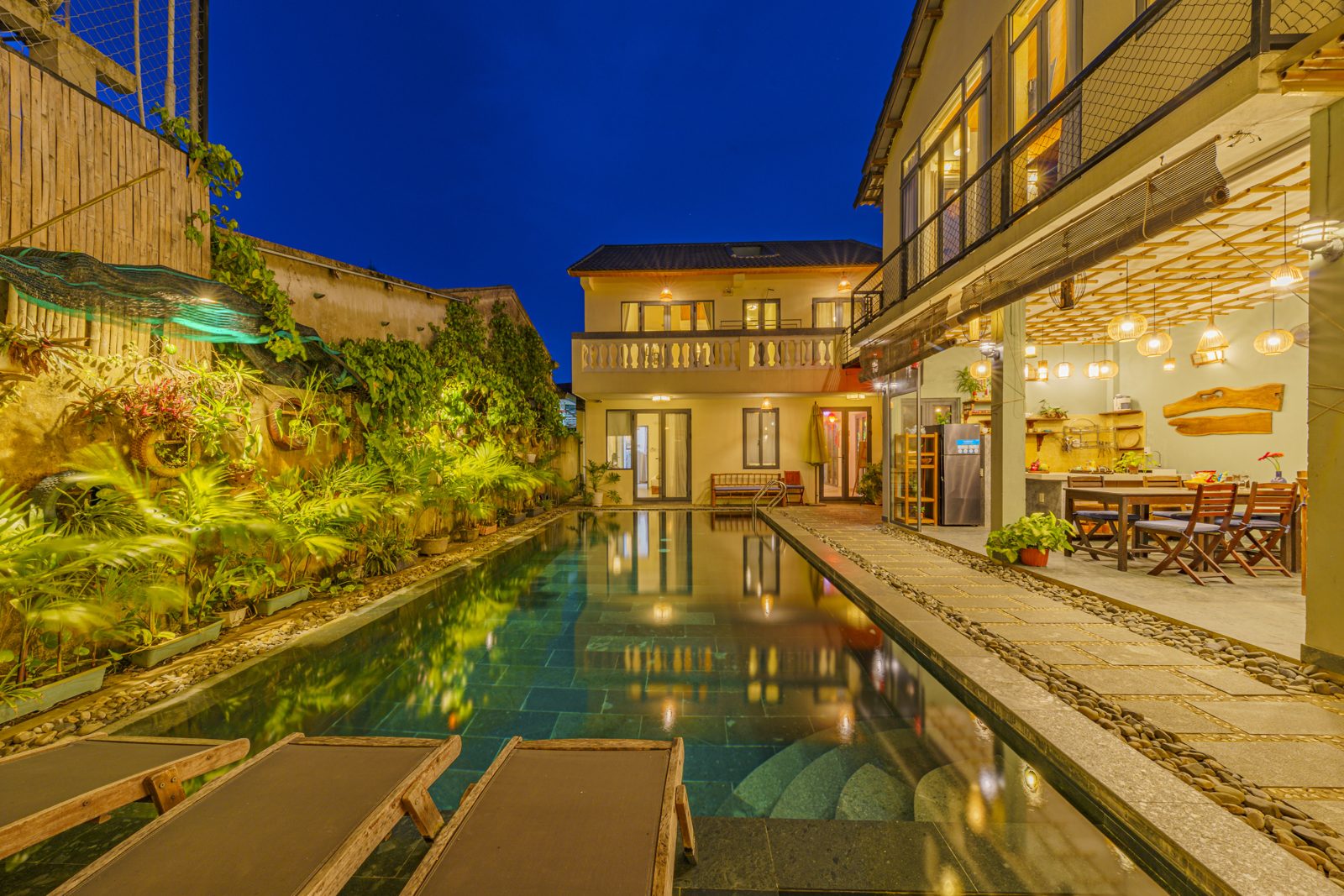 May Villa shared pool at night with loungers and a planted wall