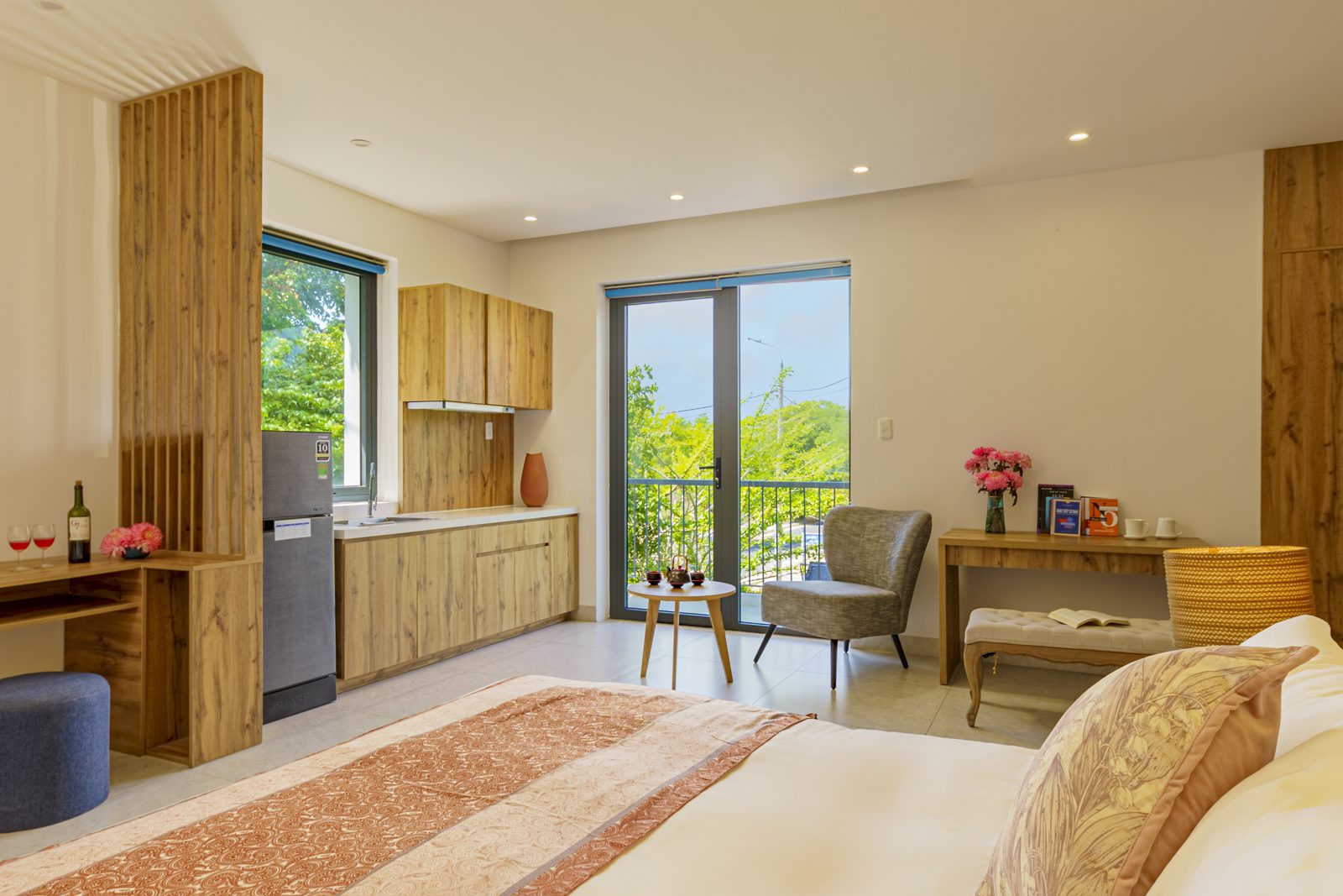 Large room with kitchenette, desk, armchair and balcony door