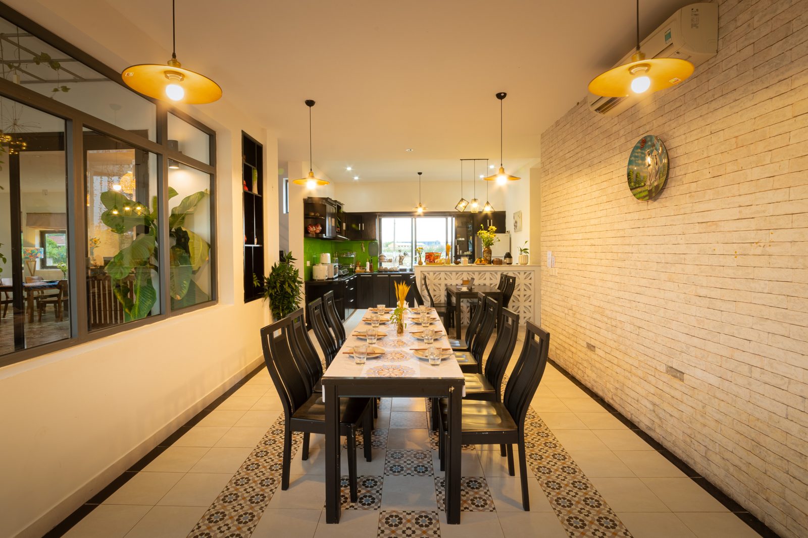 Long dining table set for a group, with pendant lights and patterned tiles
