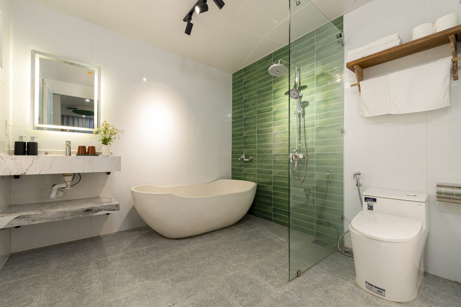 White bathroom with freestanding bathtub and green-tiled shower