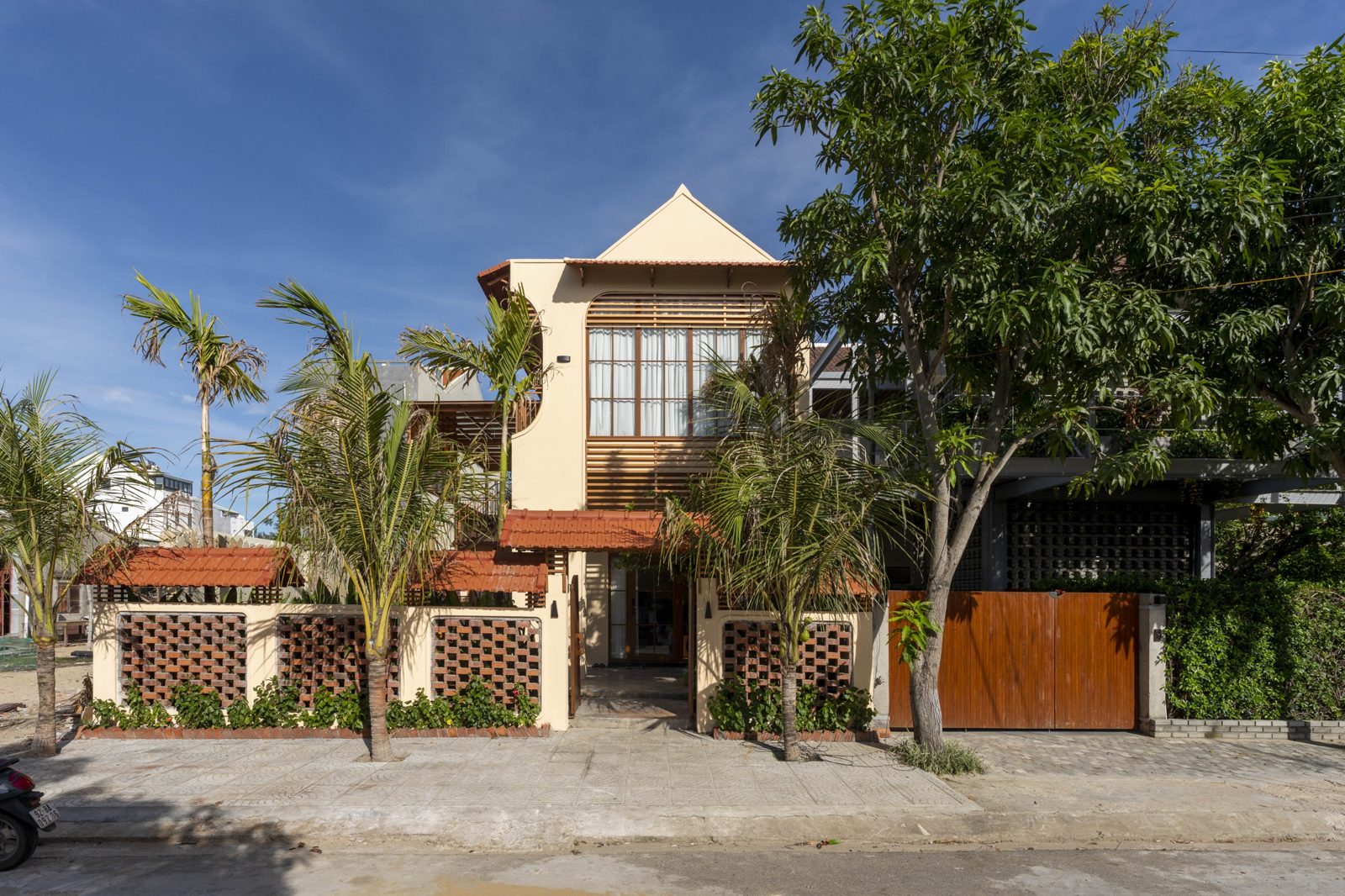 Hova Villa façade with terracotta roofs, breeze-block wall and coconut palms