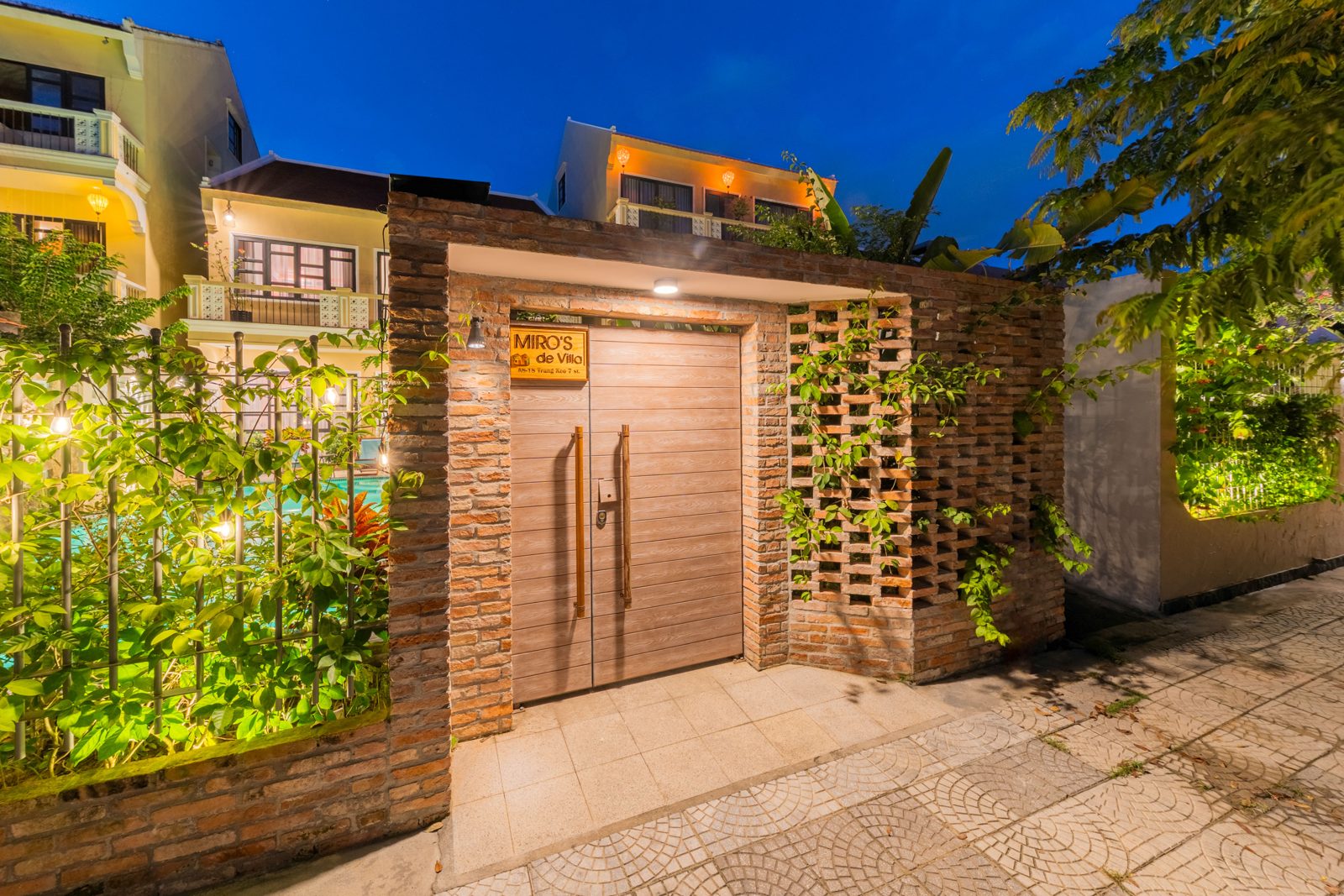 Miro de Villa entrance at dusk, wooden gate and patterned brick wall lit up