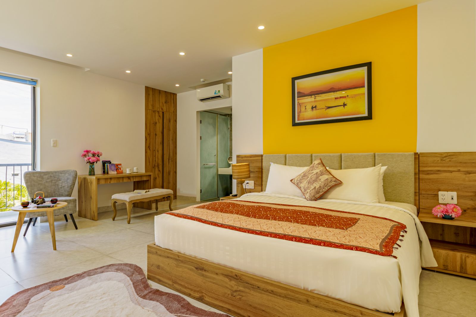 Bedroom with yellow accent wall, oak headboard and seating corner