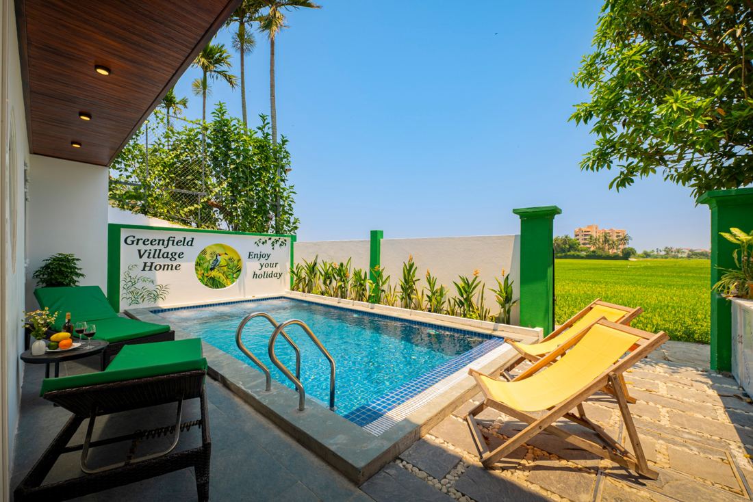 Greenfield Villa pool with green and yellow loungers opening onto rice fields