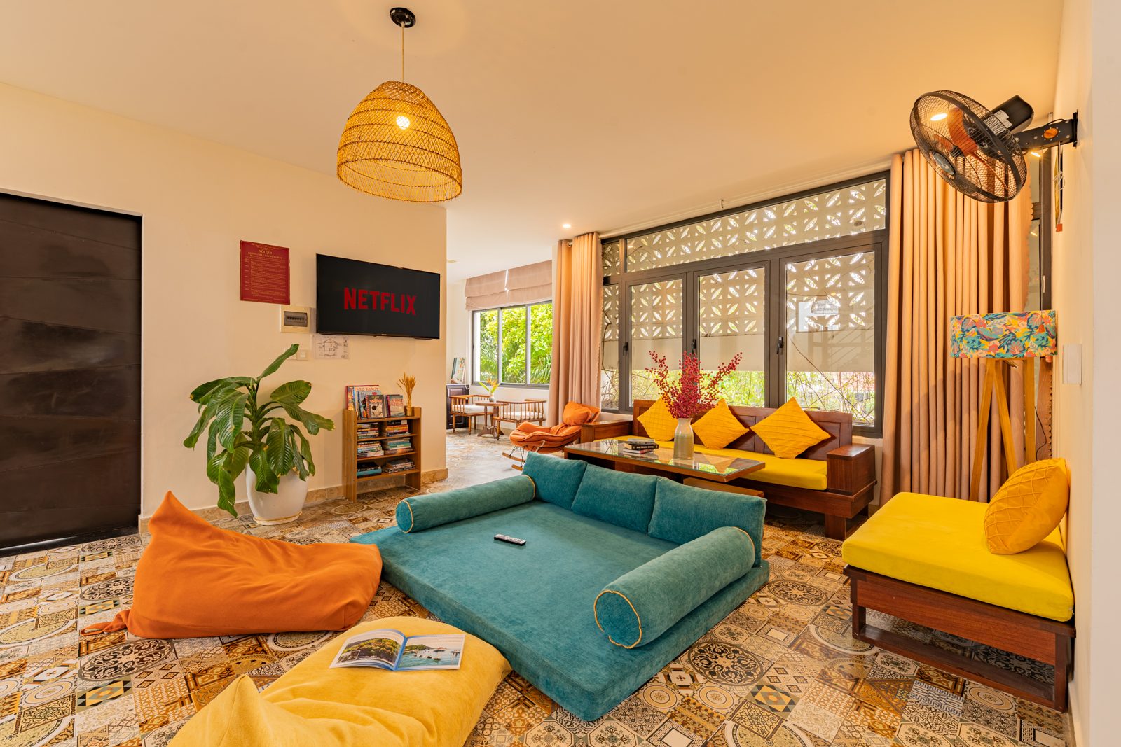 Open living room with teal sofa, orange bean bags and patterned floor