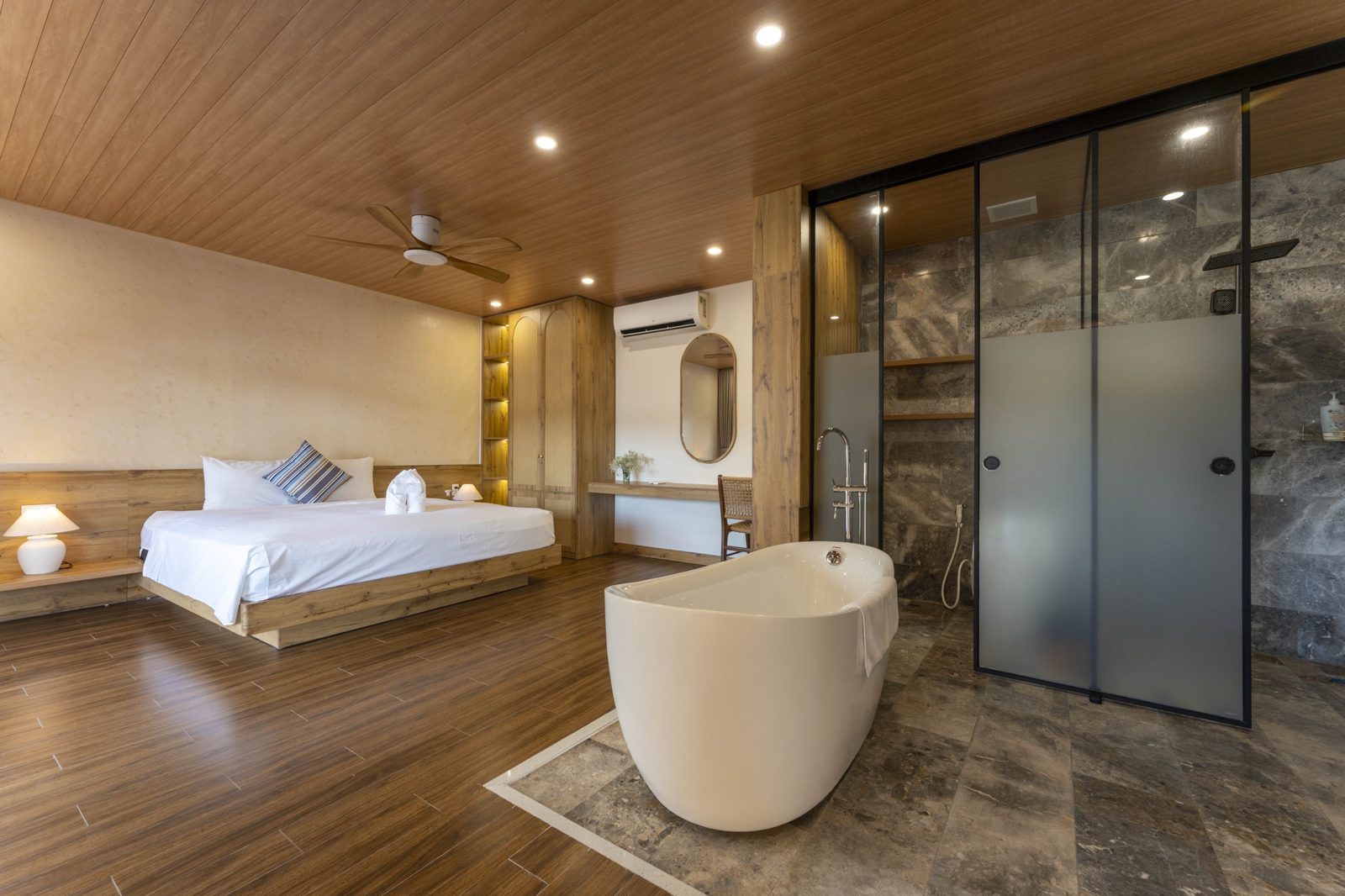 Bedroom with a freestanding bathtub on a stone platform
