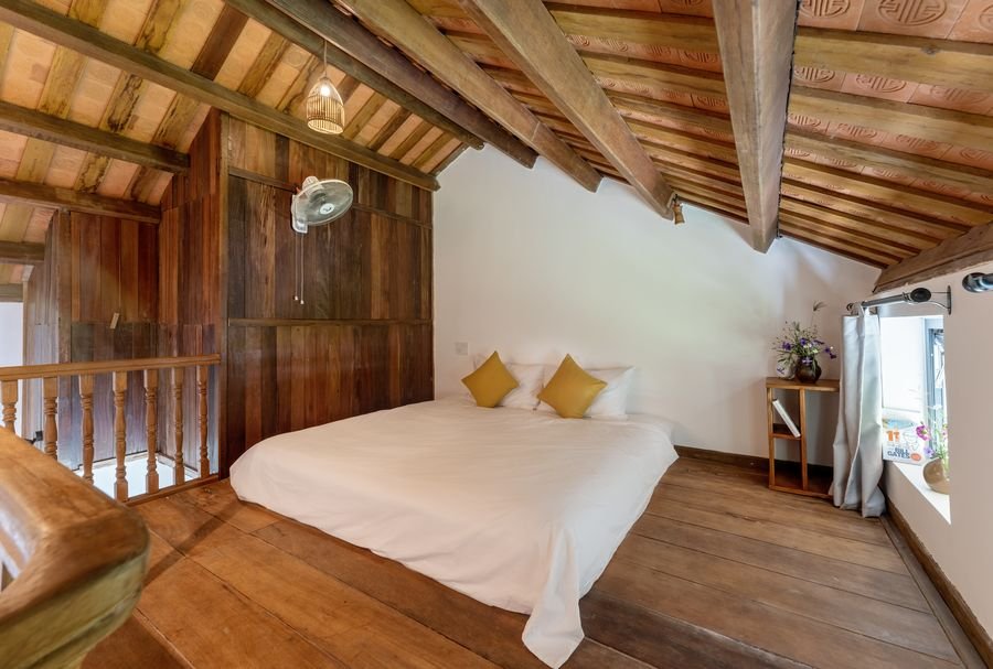 Attic bedroom under timber rafters with yellow cushions