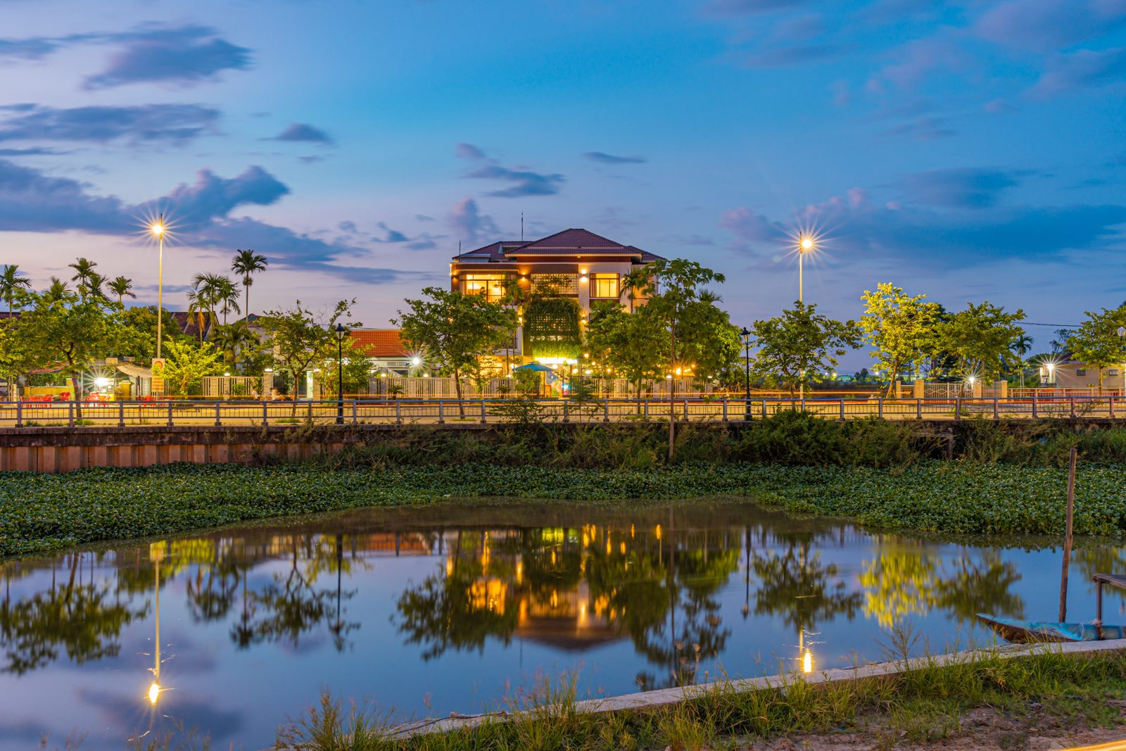 Gateway Inn at dusk, lit up and reflected in the flooded rice field in front