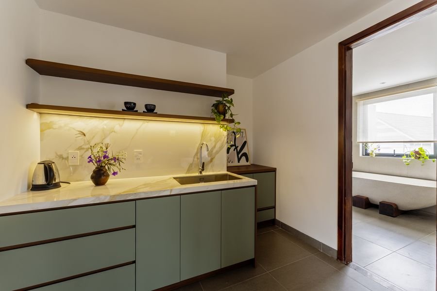 Studio kitchenette with sage cabinets and open shelving