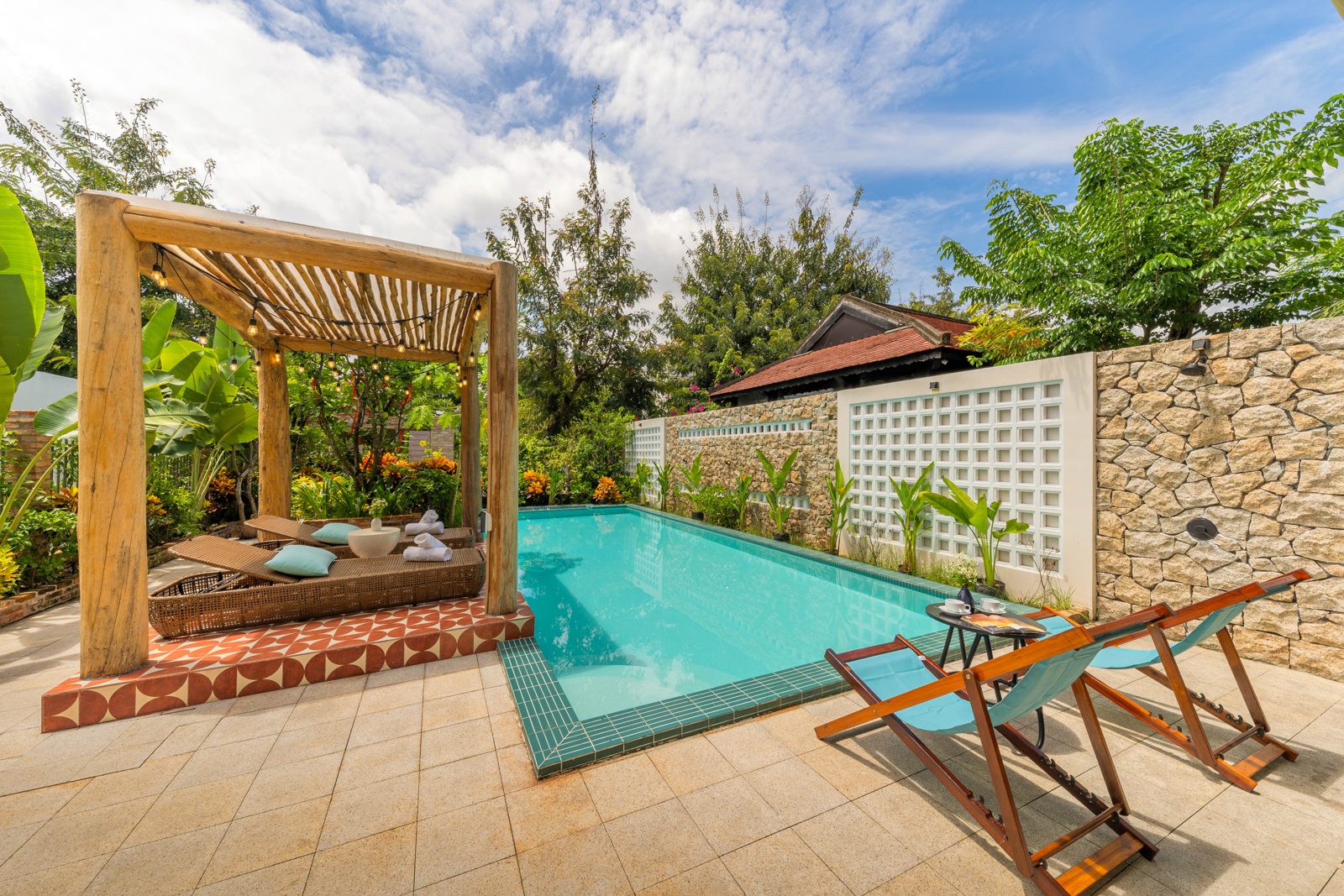 Wooden pavilion beside the pool, deck chairs and a stone garden wall