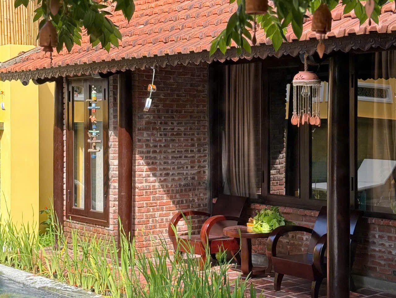 Brick house veranda with wooden chairs under the red-tiled eaves
