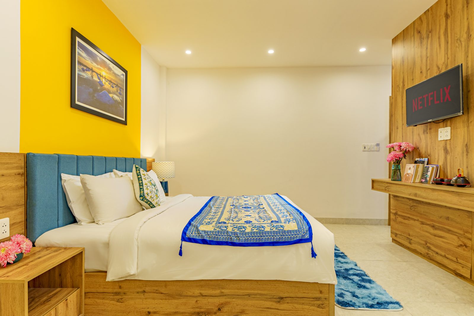 Bedroom with blue headboard, yellow wall and painting