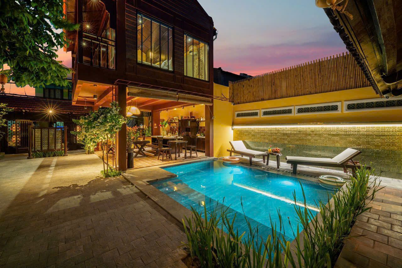 De Min Villa pool at dusk beside the wooden stilt house