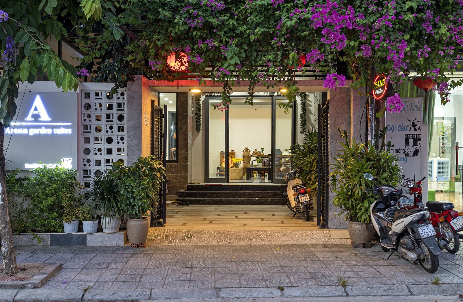 Aroma Garden Suites entrance at dusk, purple bougainvillea and red lanterns