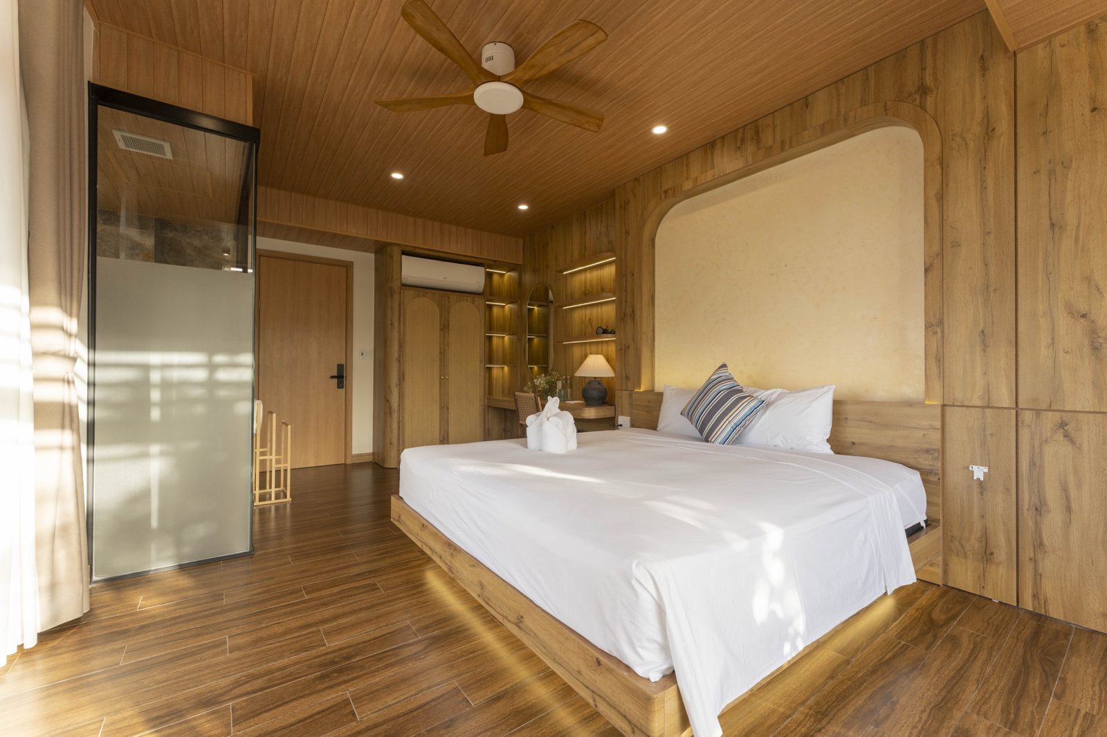 Bedroom with floating bed, arched headboard niche and wood-panelled ceiling