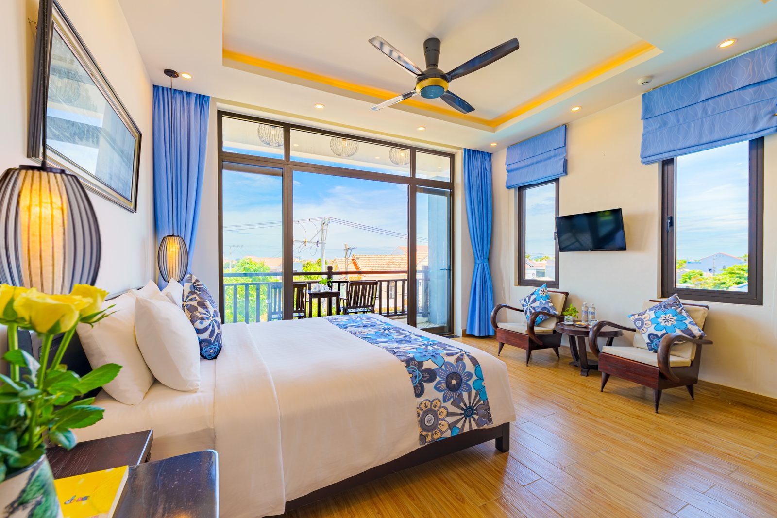 Bedroom with batik throw, ceiling fan and windows onto the river