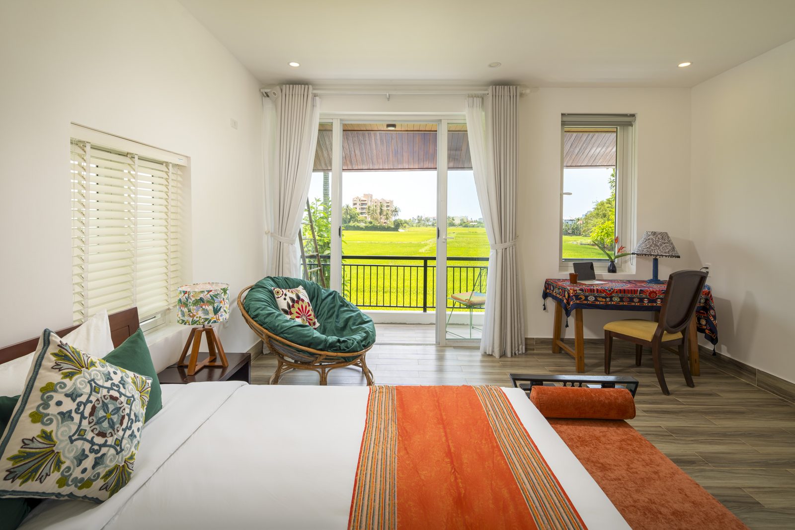 Bedroom with orange throw and glass doors onto the rice fields