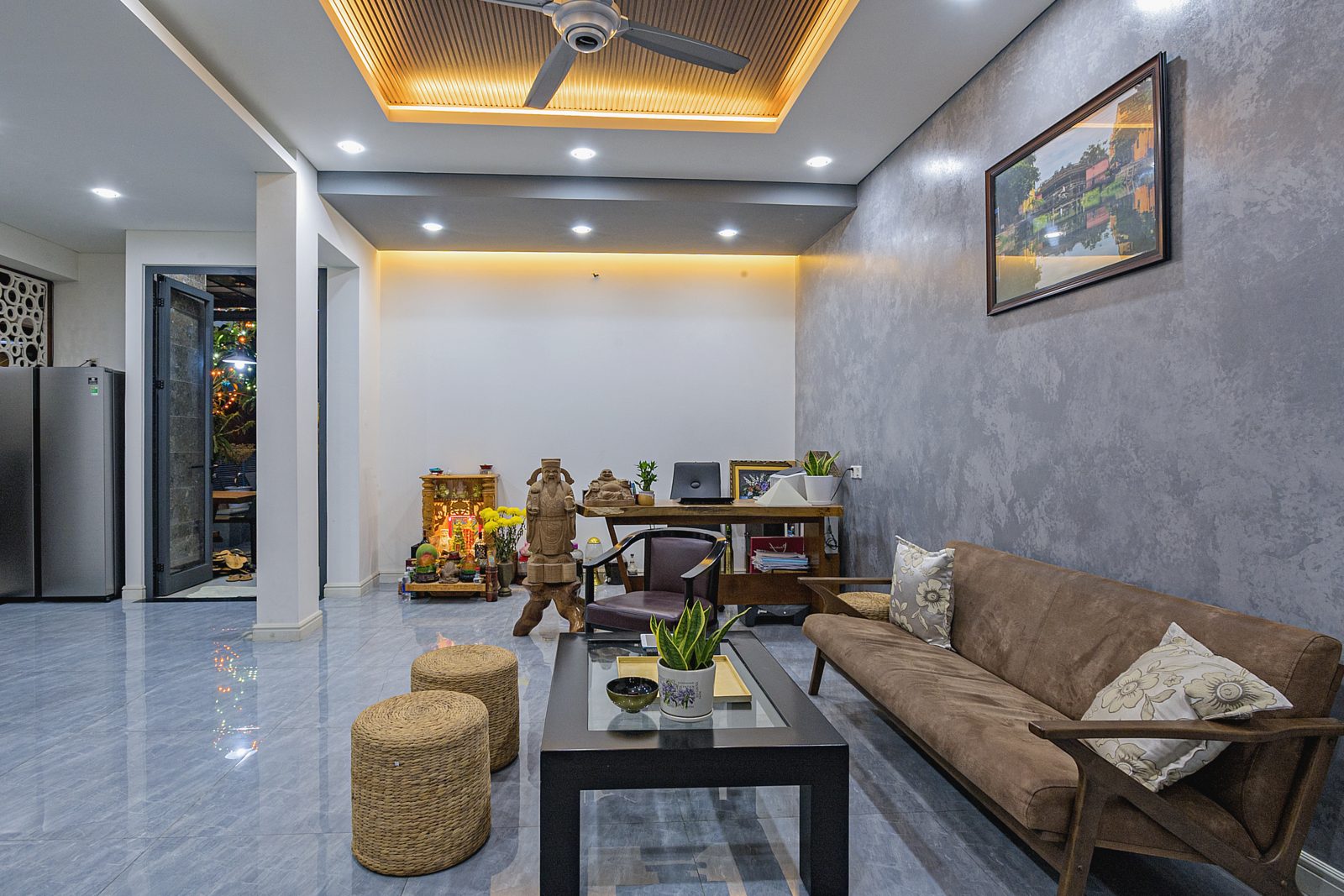 Living room with leather sofa, rattan stools and cove-lit ceiling
