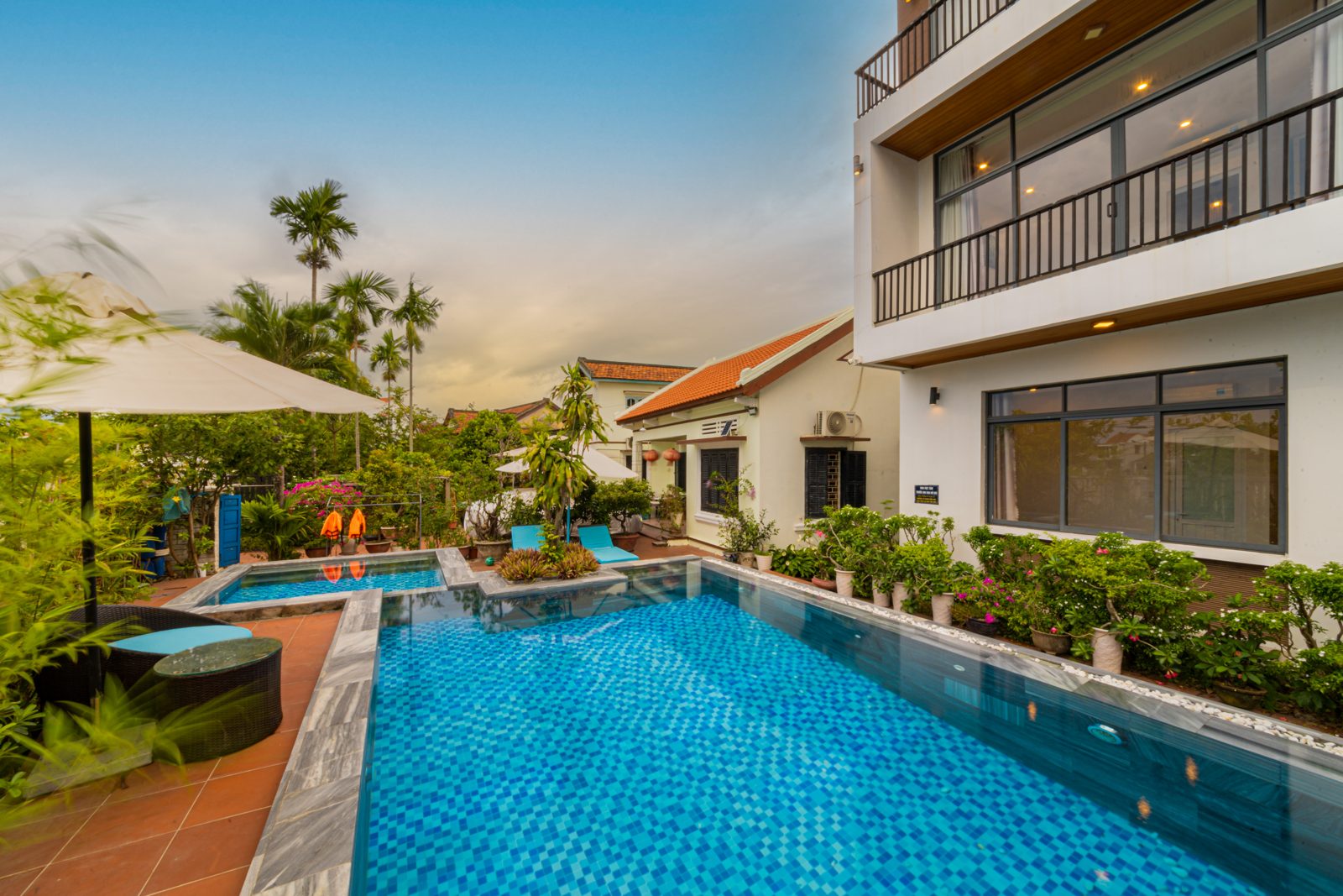 Gateway Inn's long blue pool with loungers, umbrellas and garden