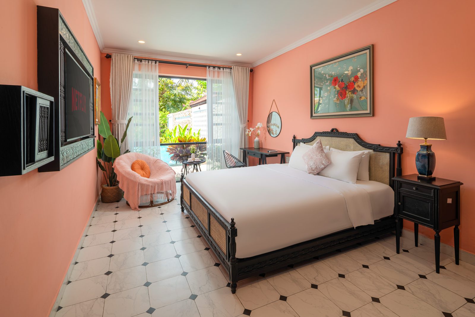 Coral bedroom with a dark wood bed and garden doors