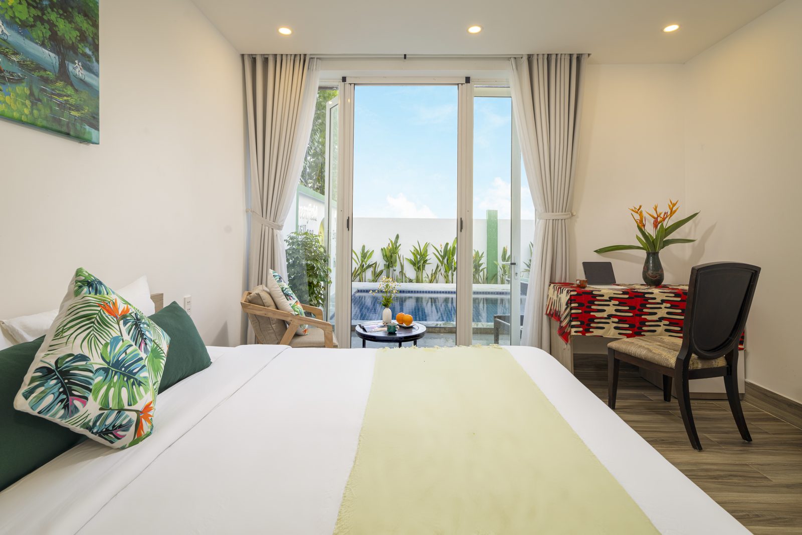 Bed with tropical cushions facing glass doors to the pool