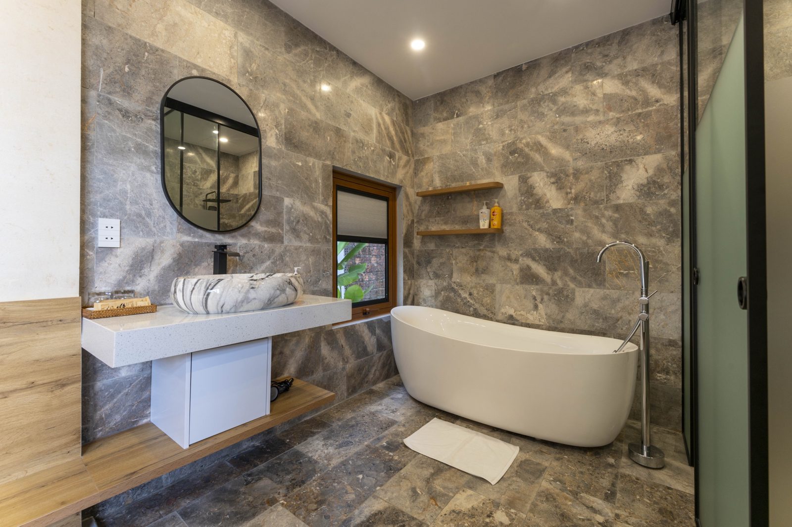 Grey stone bathroom with a freestanding bathtub and marble basin