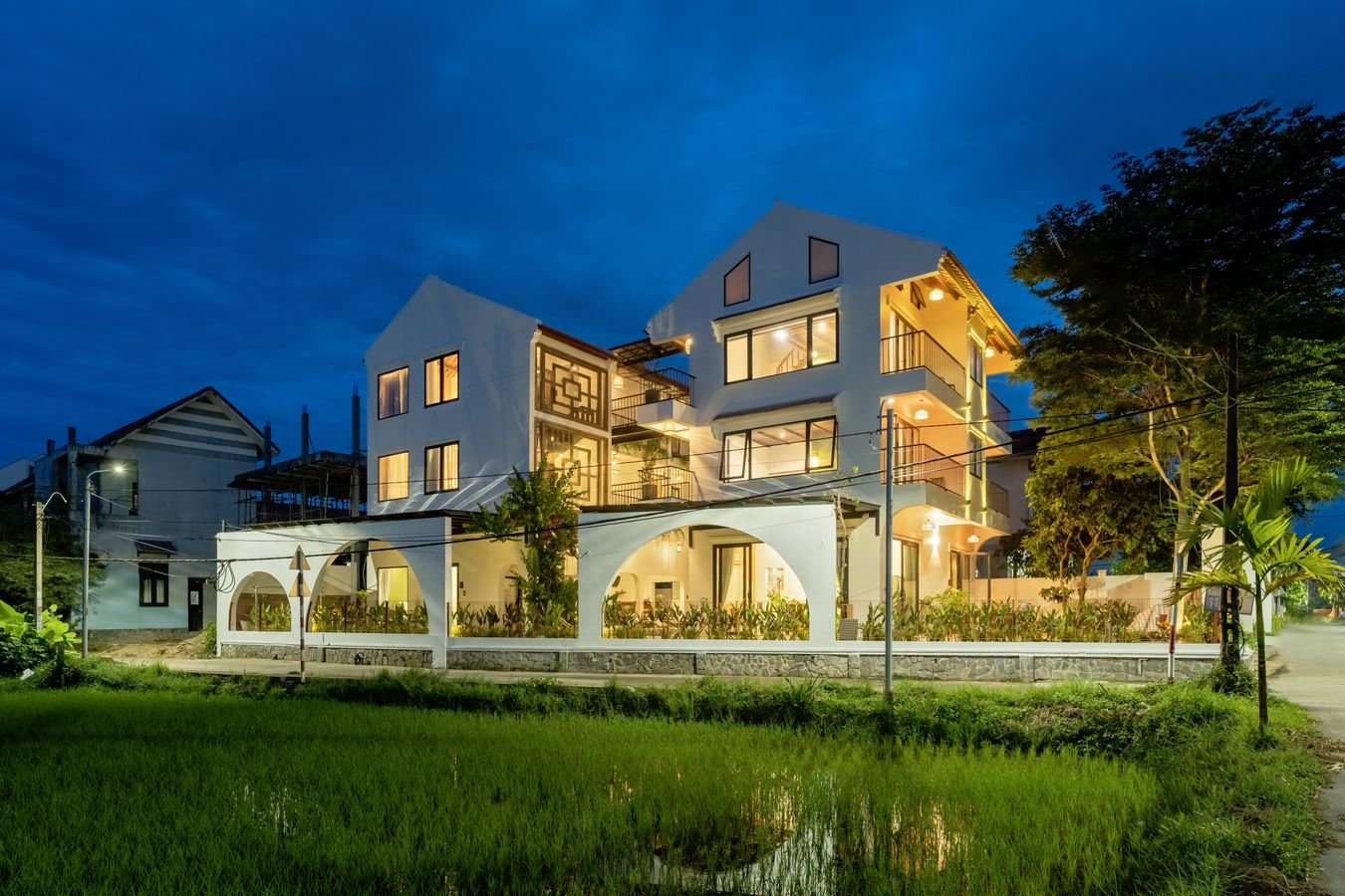 Maison de Chinh lit up at blue hour behind rice fields