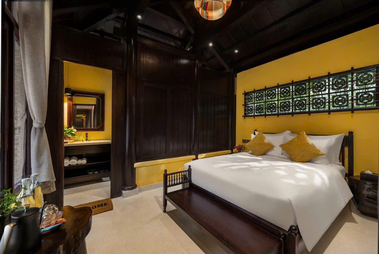 Bedroom with mustard walls, carved wood screen and a white bed